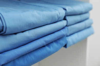 Light blue medical uniforms on white rack, closeup