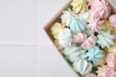 Photo of Tasty meringue cookies on white tiled table, top view. Space for text