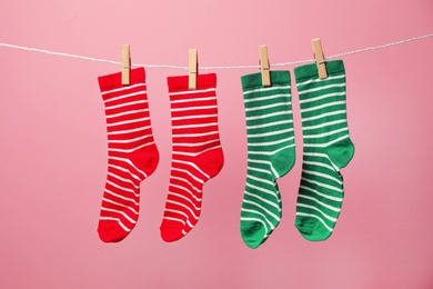 Different socks on laundry line against color background