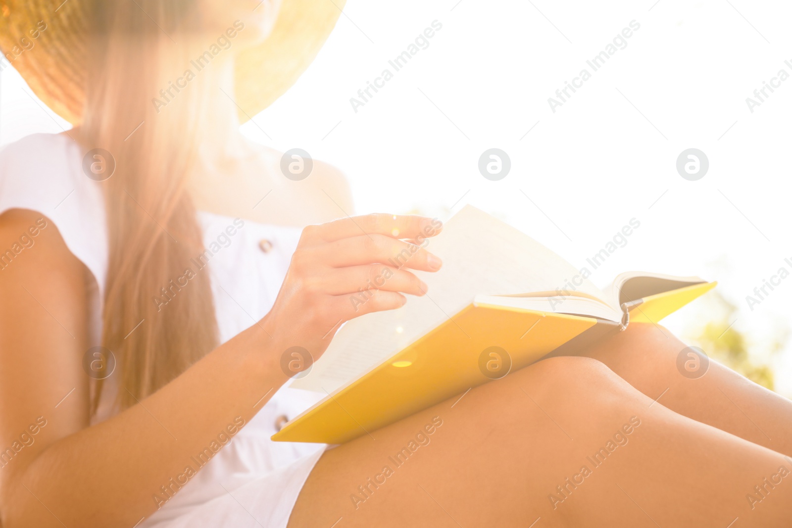 Photo of Young woman reading book outdoors, closeup view