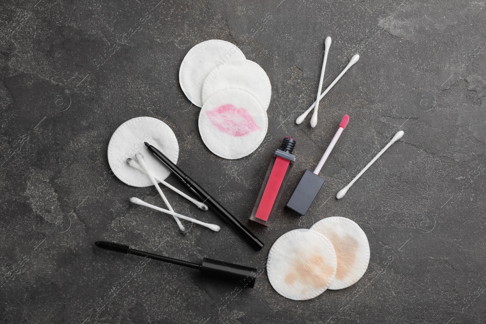 Photo of Dirty cotton pads, swabs and cosmetic products on grey background, flat lay