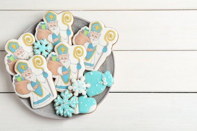 Tasty gingerbread cookies on white wooden table, top view with space for text. St. Nicholas Day celebration