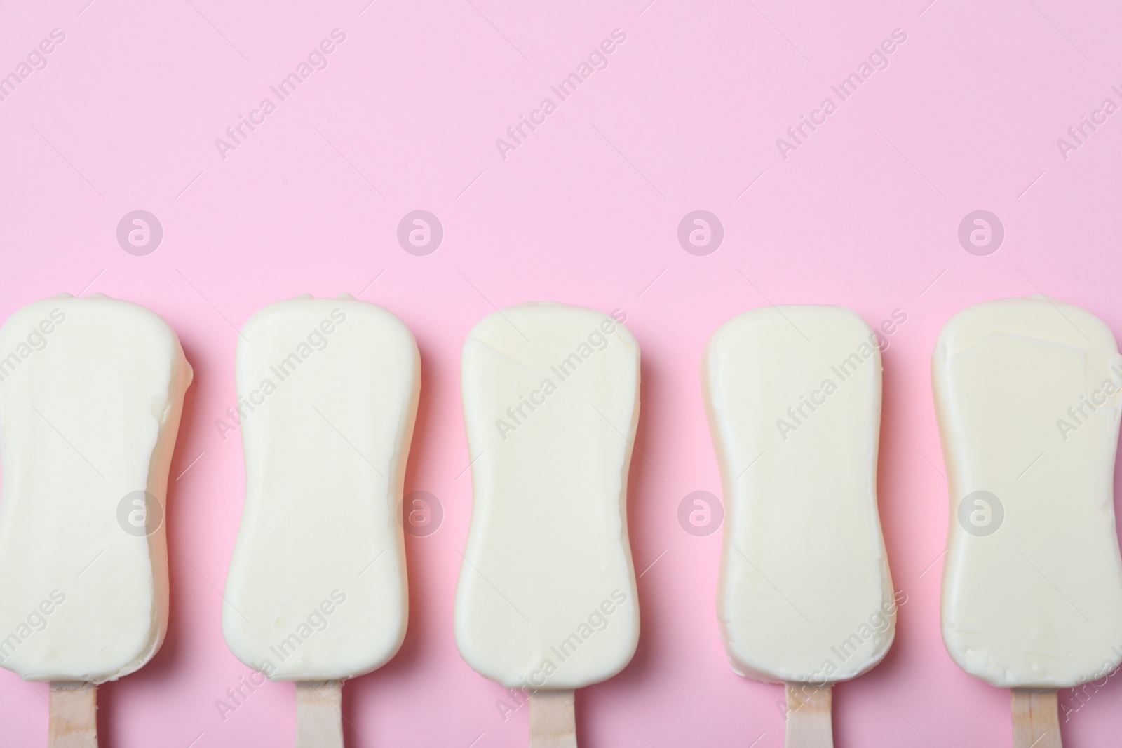 Photo of Glazed ice cream bars on pink background, flat lay. Space for text