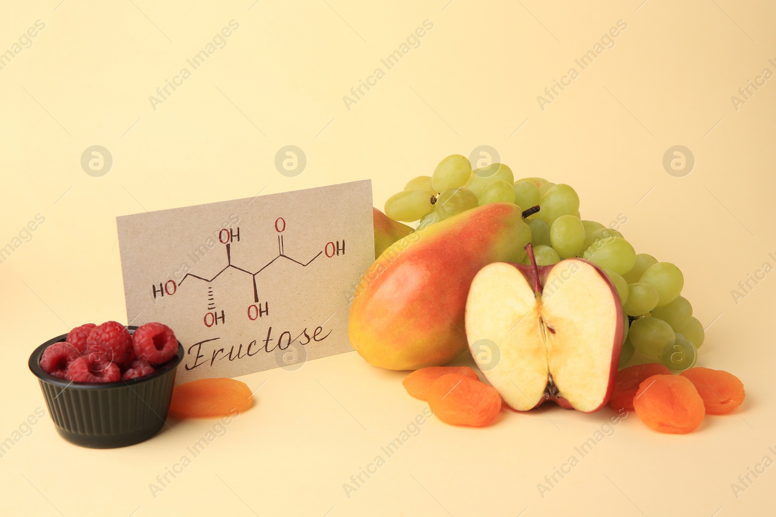 Photo of Card with word Fructose, delicious ripe fruits, raspberries and dried apricots on beige background