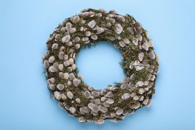 Wreath made of beautiful willow flowers on light blue background, top view