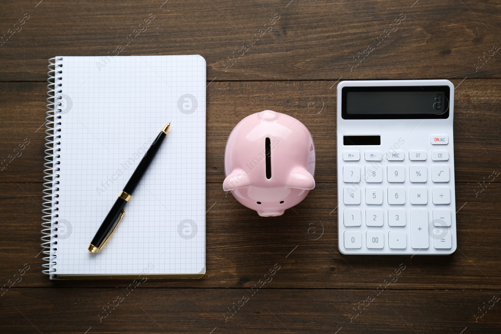 Photo of Calculator, piggy bank and notebook on wooden table, flat lay