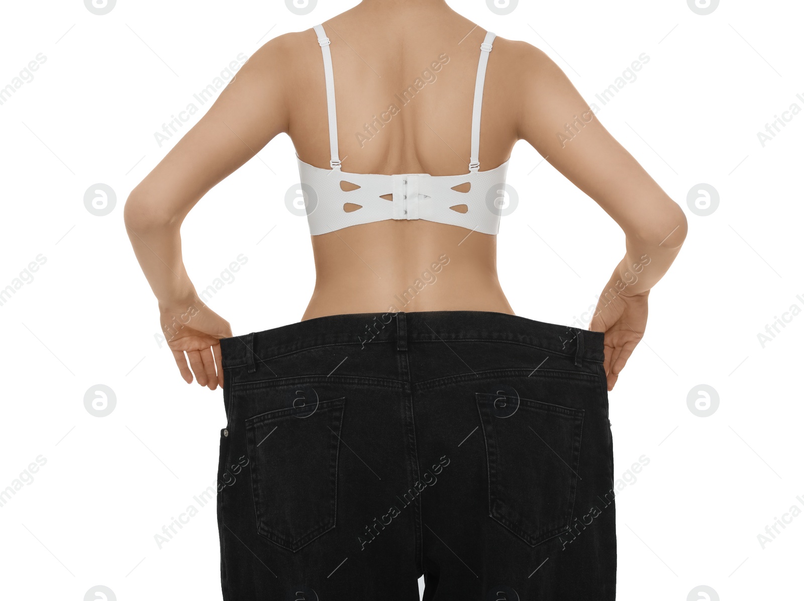 Photo of Young woman wearing big jeans after weight loss on white background, closeup