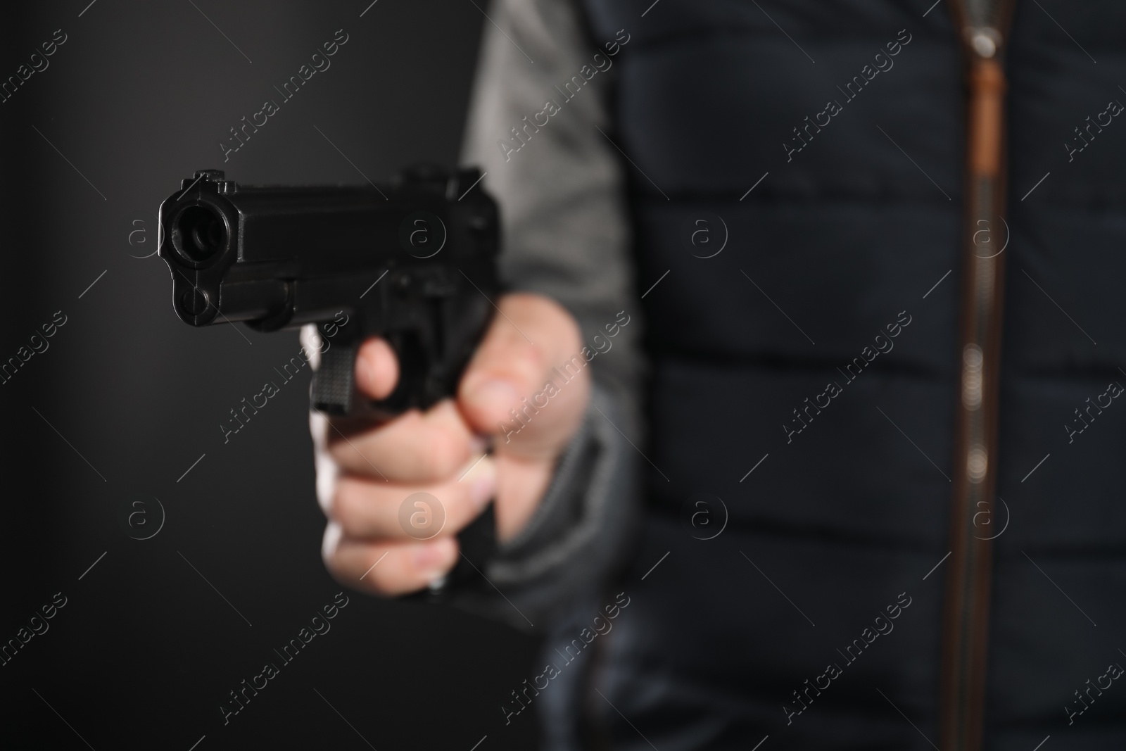 Photo of Dangerous criminal with gun on black background, closeup. Armed robbery