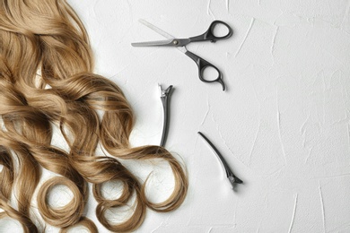 Flat lay composition with curly hair locks and tools on light background. Space for text