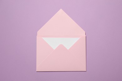 Letter envelope with card on violet background, top view