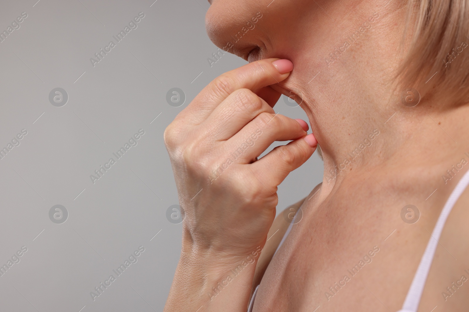 Photo of Woman touching her neck on grey background, closeup