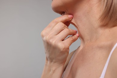 Photo of Woman touching her neck on grey background, closeup