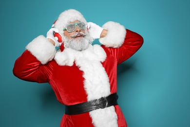 Photo of Santa Claus listening to Christmas music on color background