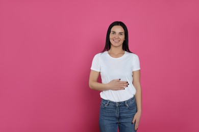 Photo of Happy woman touching her belly on pink background, space for text. Concept of healthy stomach