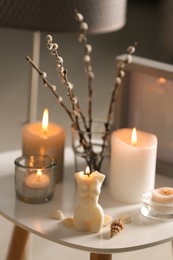 Photo of Beautiful body shaped candles and willow bouquet on table indoors