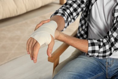 Photo of Man with hand wrapped in medical bandage indoors, closeup