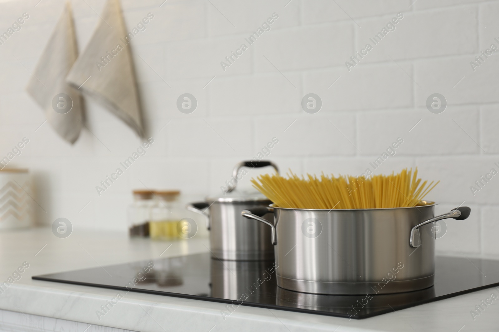 Photo of Saucepan with uncooked pasta on stove in kitchen