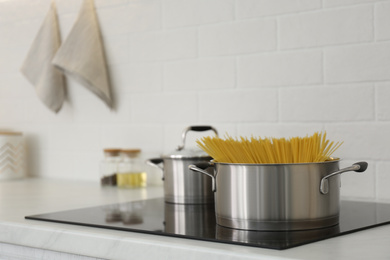 Saucepan with uncooked pasta on stove in kitchen