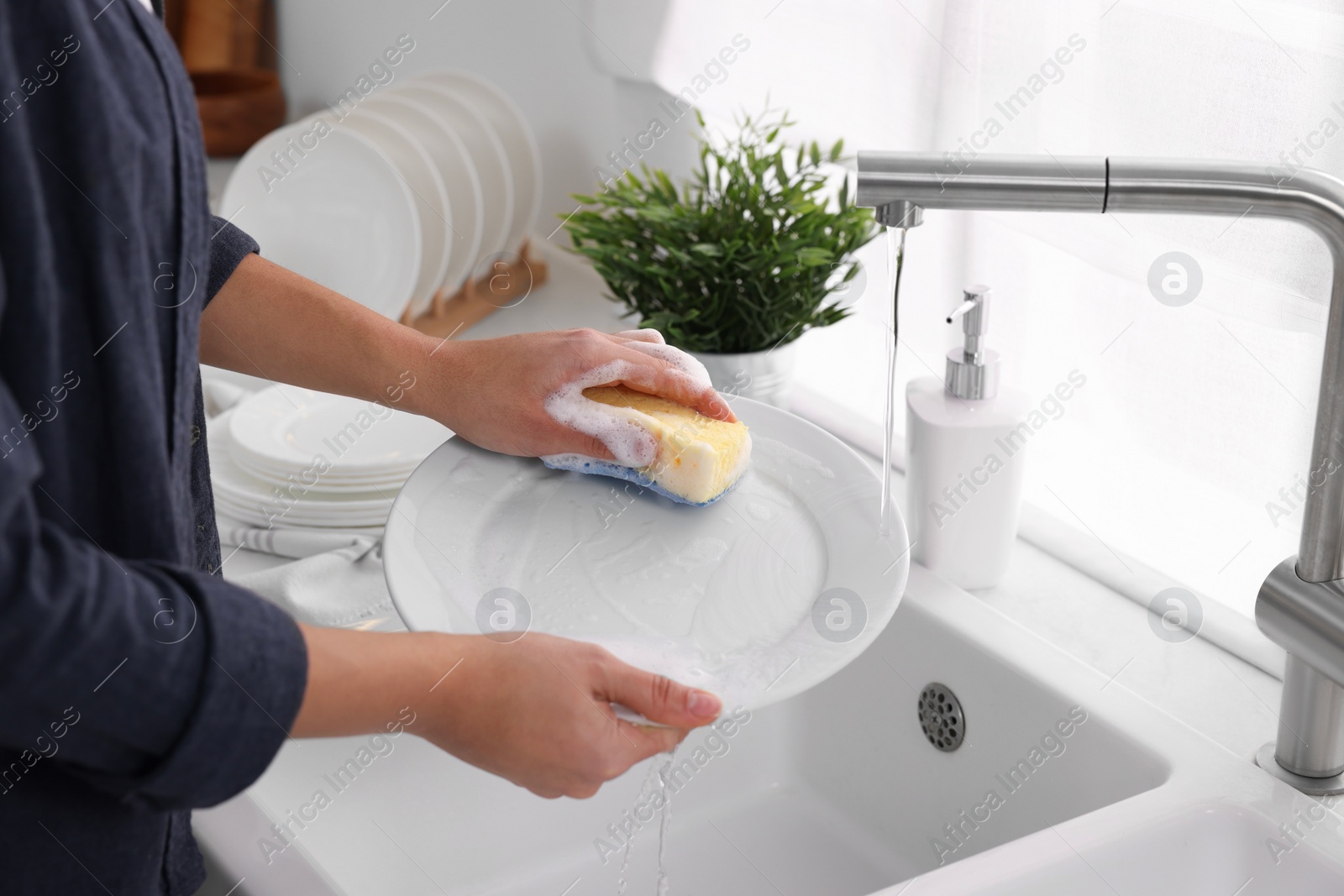 Photo of Woman washing plate at sink in kitchen, closeup