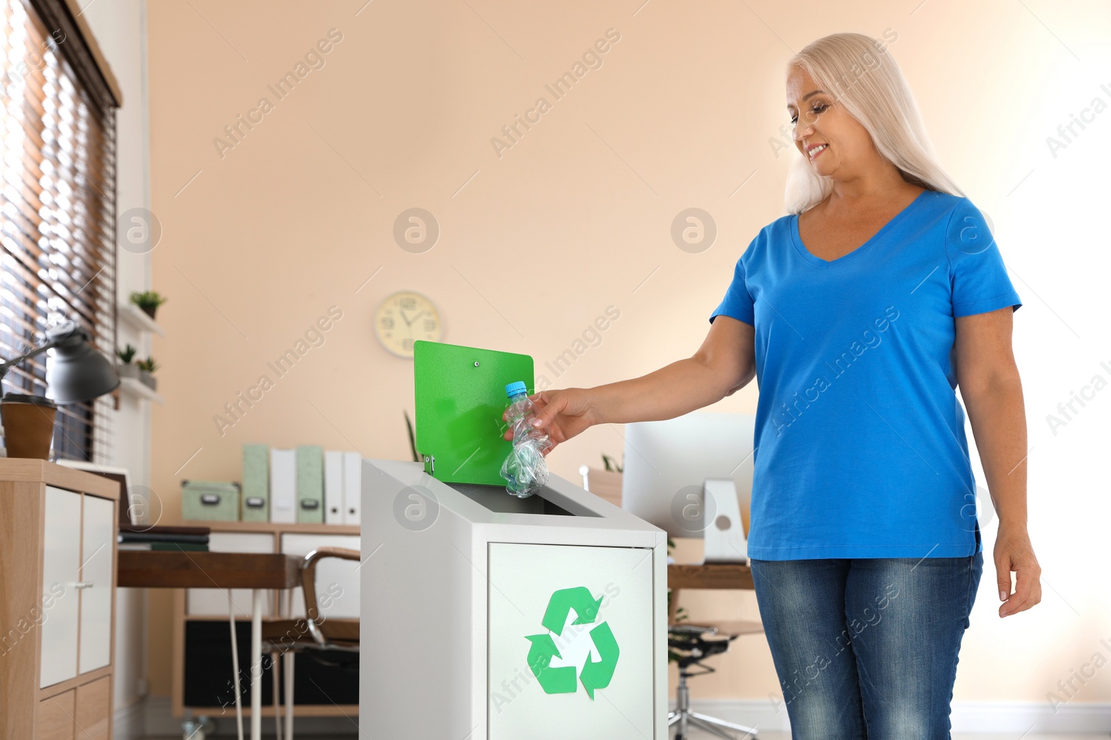 Photo of Woman throwing plastic bottle into recycling bin at office