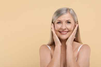 Portrait of beautiful senior woman on beige background. Space for text