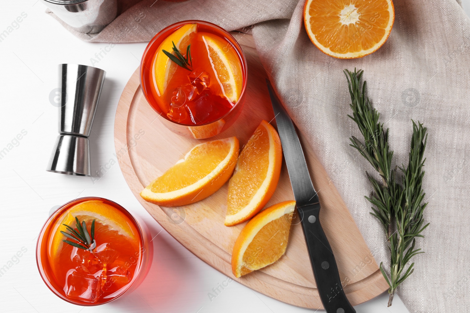 Photo of Aperol spritz cocktail, rosemary and orange slices on white wooden table, flat lay