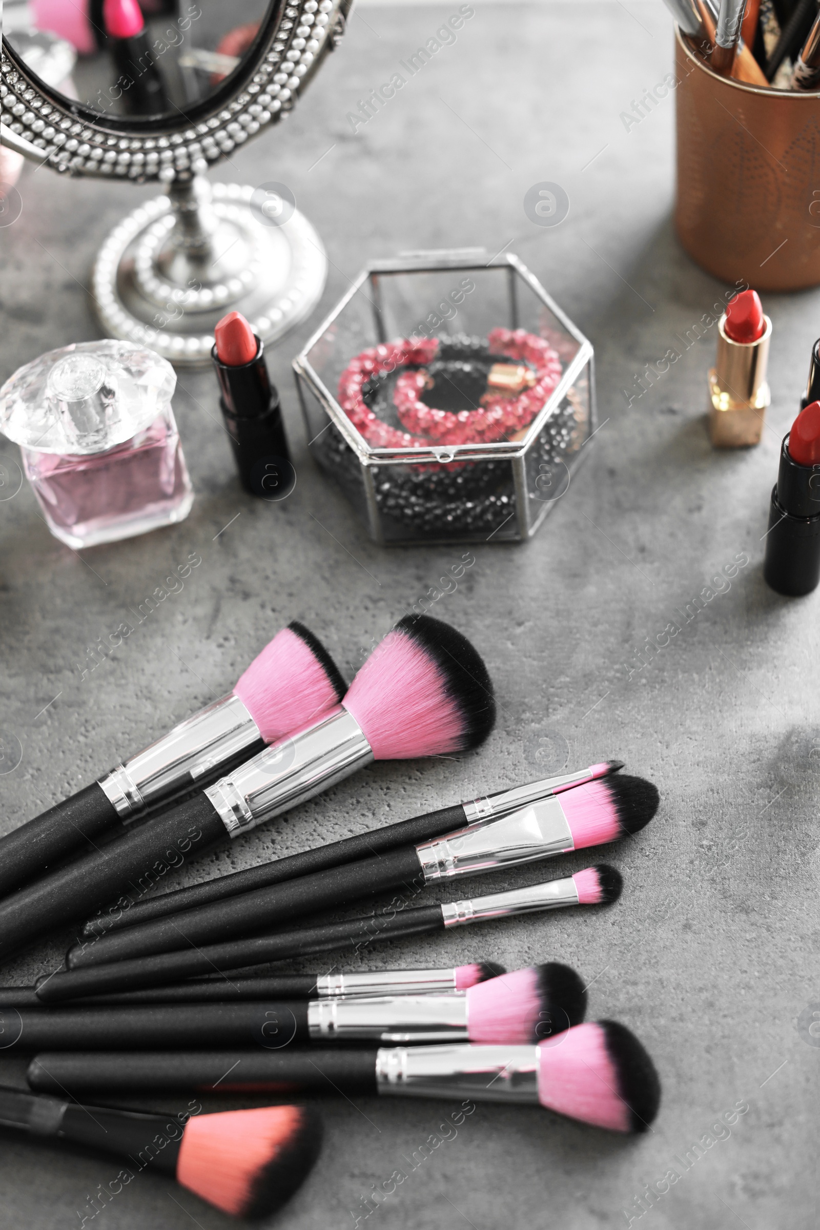 Photo of Makeup products and brushes on grey background