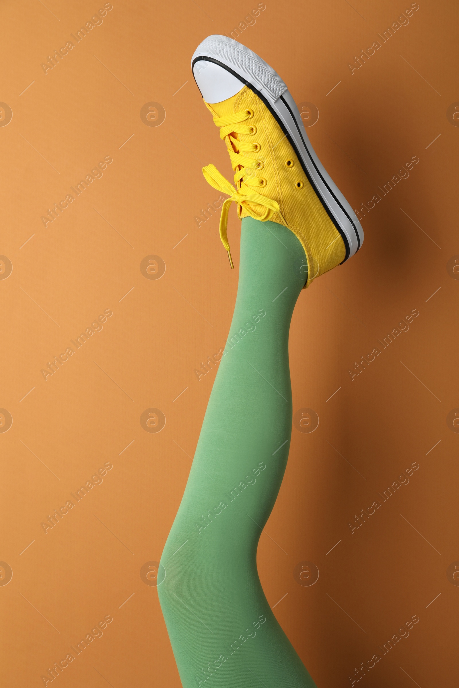 Photo of Woman wearing shoes on orange background, closeup