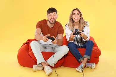 Photo of Emotional couple playing video games with controllers on color background