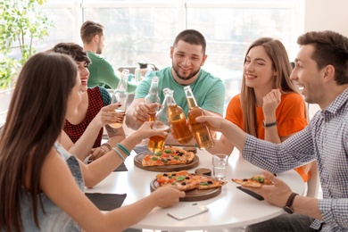 Young people having fun party with delicious pizza indoors