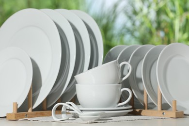 Photo of Set of clean dishware on white table against blurred background