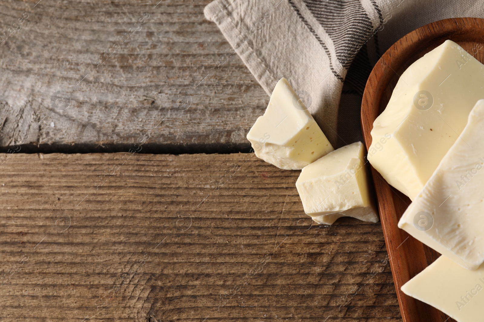 Photo of Pieces of tasty white chocolate on wooden table, top view. Space for text