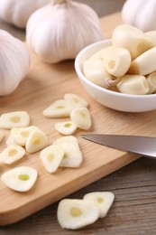 Photo of Aromatic cut garlic, cloves and bulbs on wooden table, closeup
