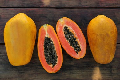 Fresh ripe cut and whole papaya fruits on wooden table, flat lay