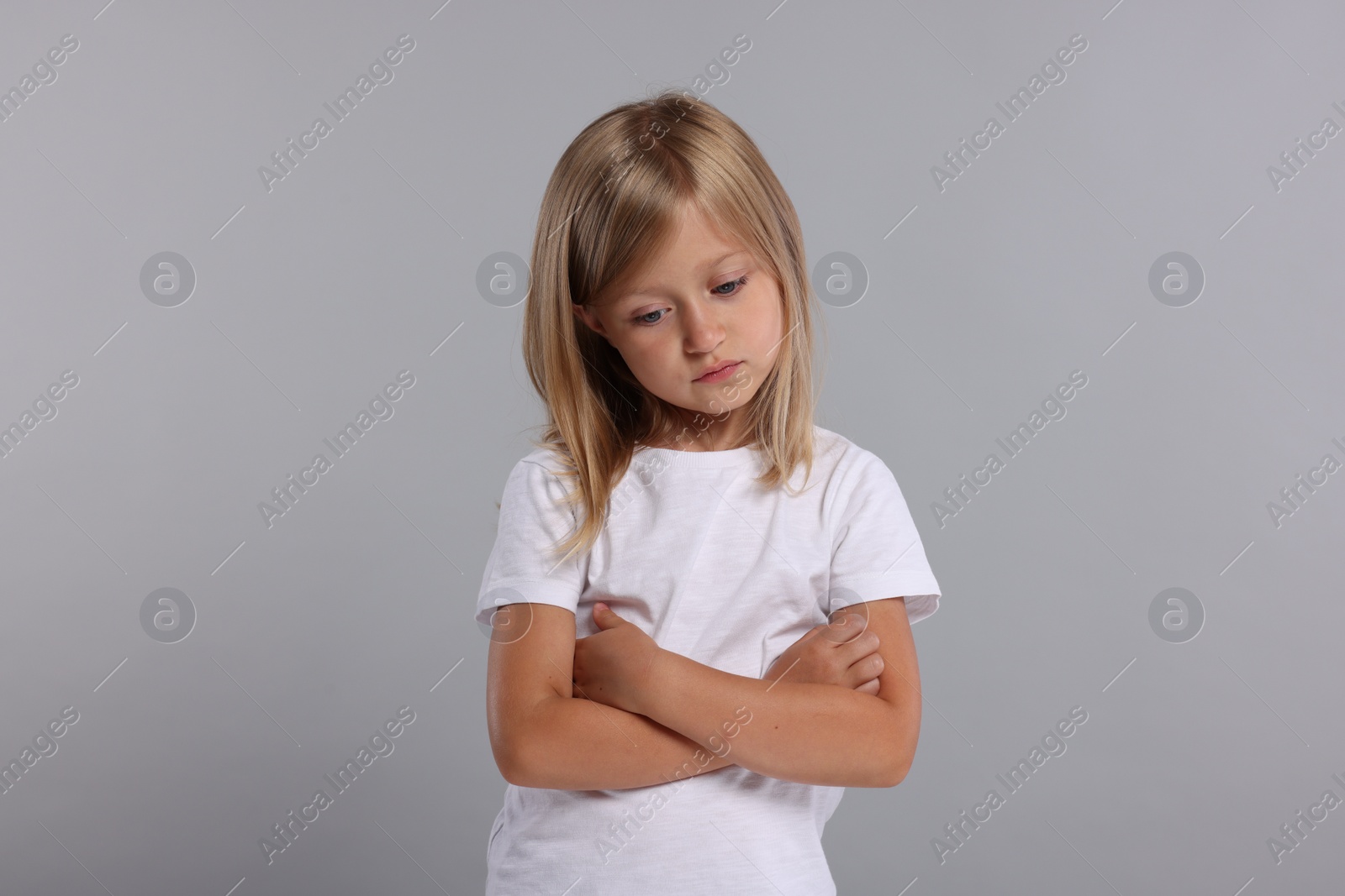 Photo of Resentful girl with crossed arms on grey background
