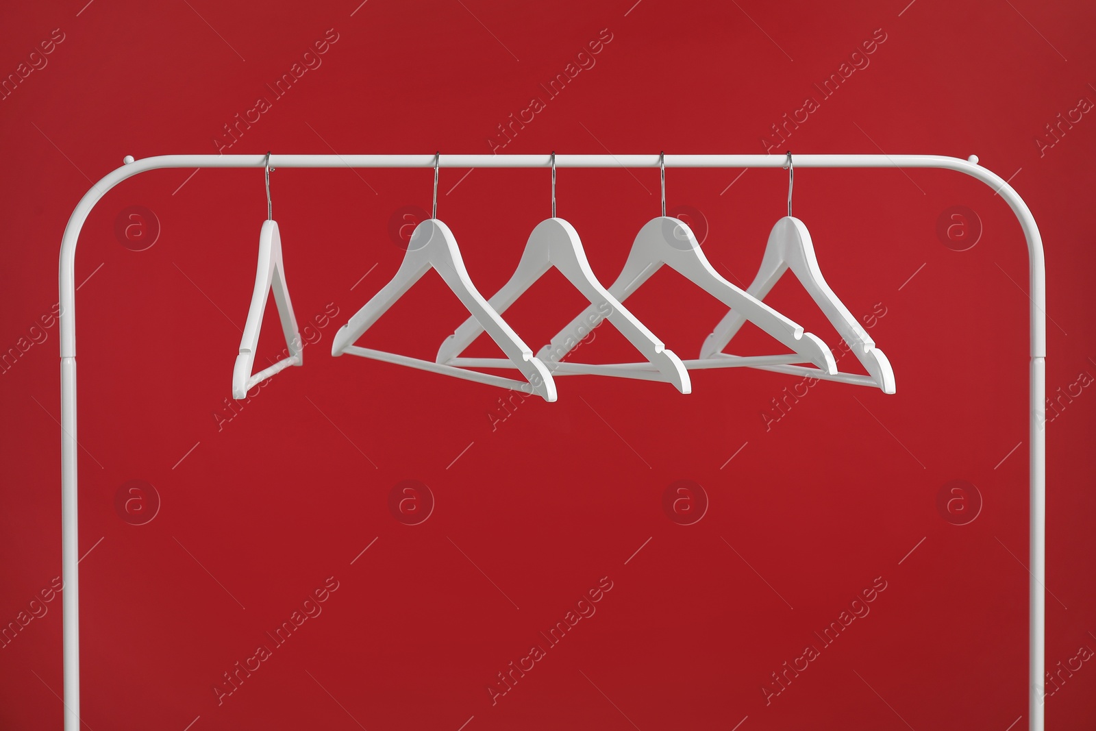 Photo of Empty clothes hangers on rack against red background