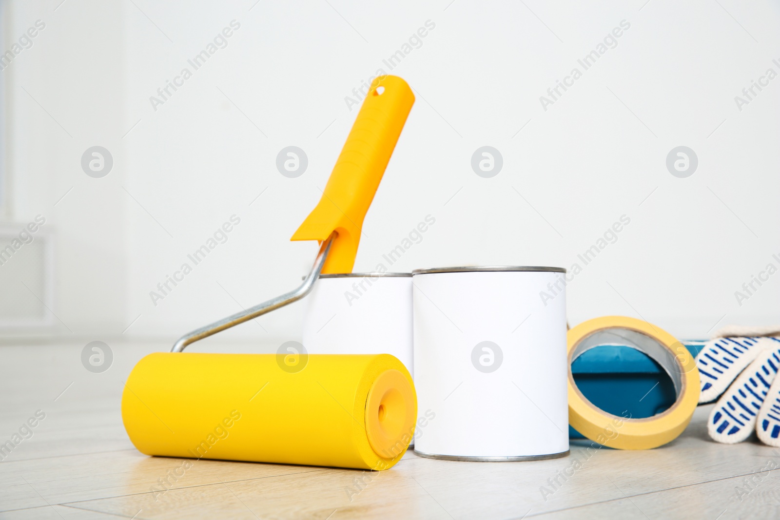 Photo of Cans of paint and decorator tools on wooden floor indoors
