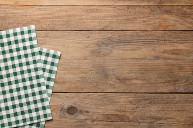 Checkered tablecloth on wooden table, top view. Space for text