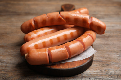 Photo of Delicious grilled sausages on wooden table, closeup