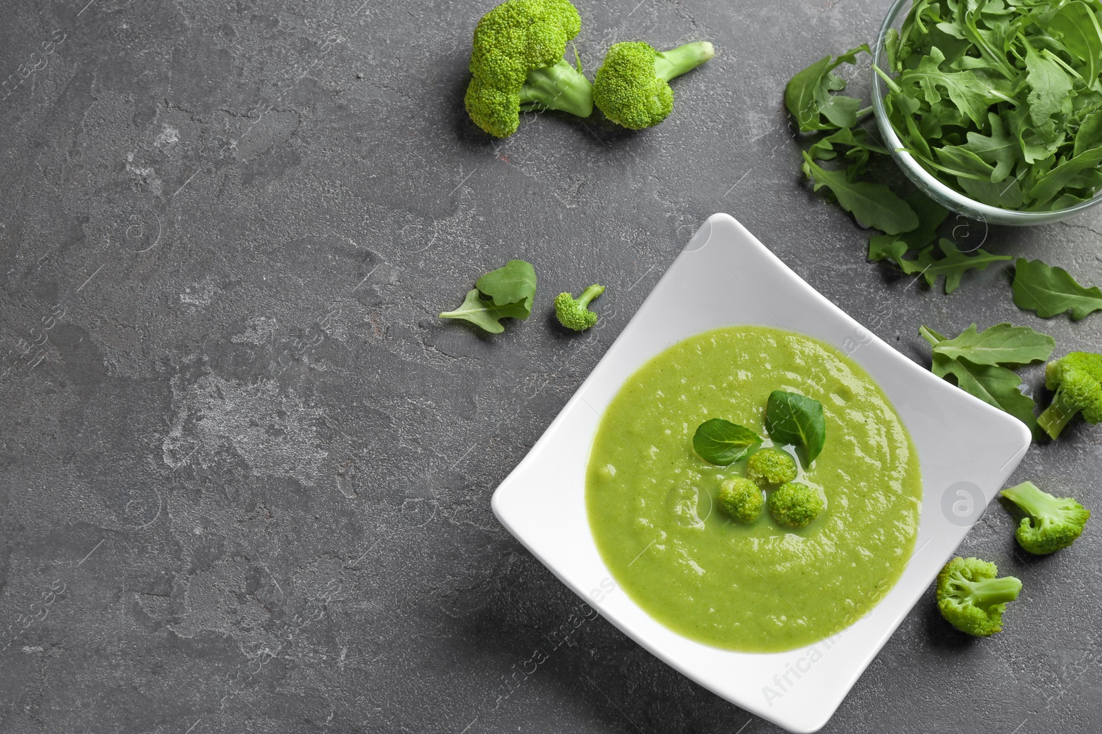 Photo of Flat lay composition with bowl of broccoli cream soup on grey table, space for text