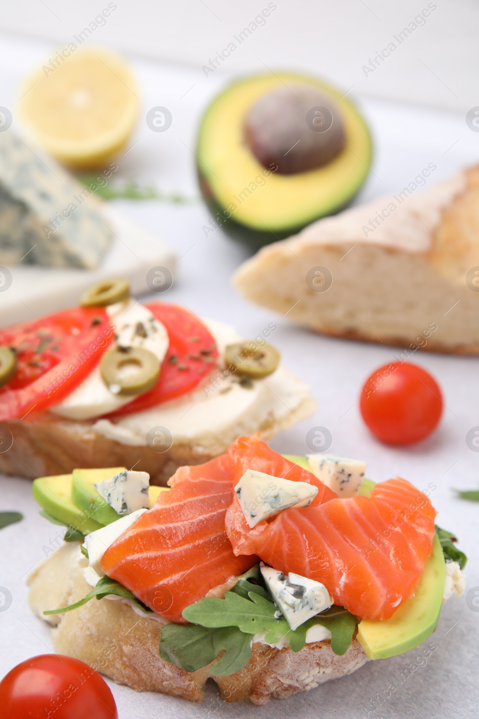 Photo of Different tasty bruschettas and ingredients on light grey textured table