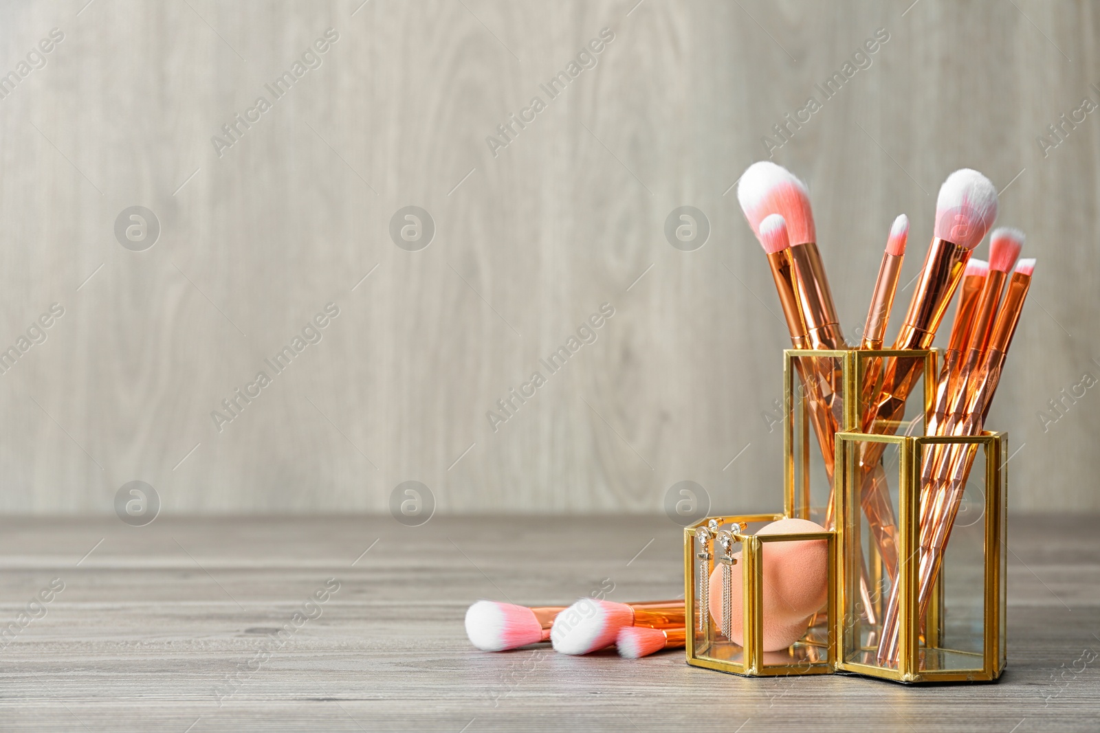 Photo of Organizer with set of professional makeup brushes and accessories on wooden table. Space for text