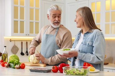 Happy senior couple cooking together in kitchen