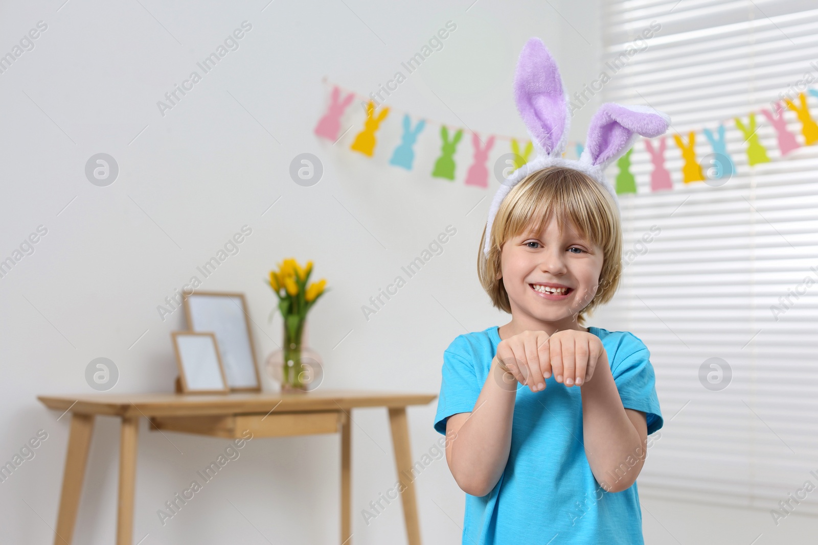 Photo of Happy boy wearing bunny ears indoors, space for text. Easter celebration