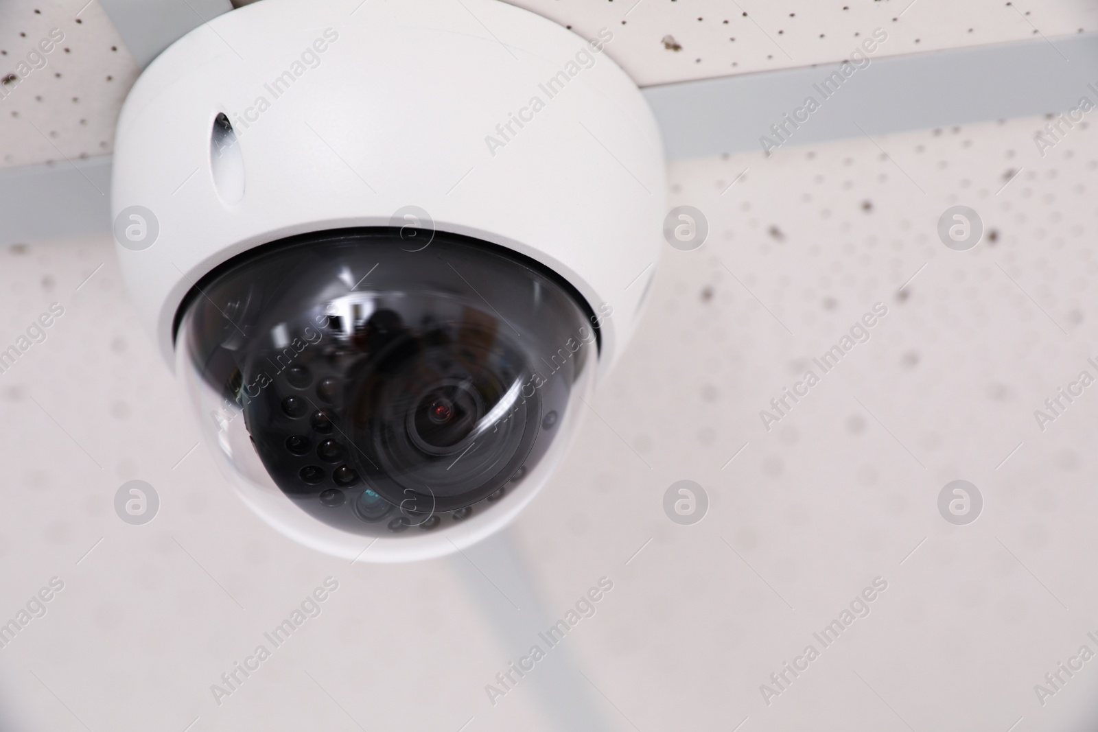 Photo of Modern security CCTV camera on ceiling in office, space for text. Protection system