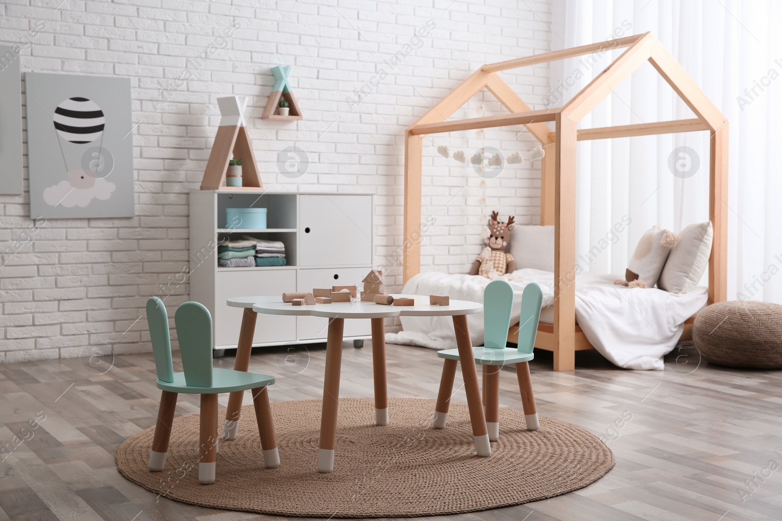 Photo of Cute children's room interior with bed and little table