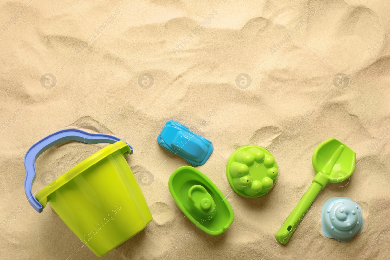 Photo of Flat lay of beach toy kit on sand, space for text. Outdoor play