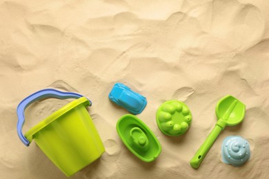 Flat lay of beach toy kit on sand, space for text. Outdoor play