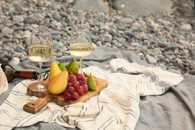 Photo of White wine and fresh fruits on picnic blanket outdoors. Space for text