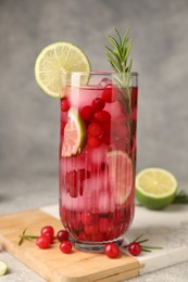 Photo of Tasty cranberry cocktail with rosemary and lime in glass on gray background